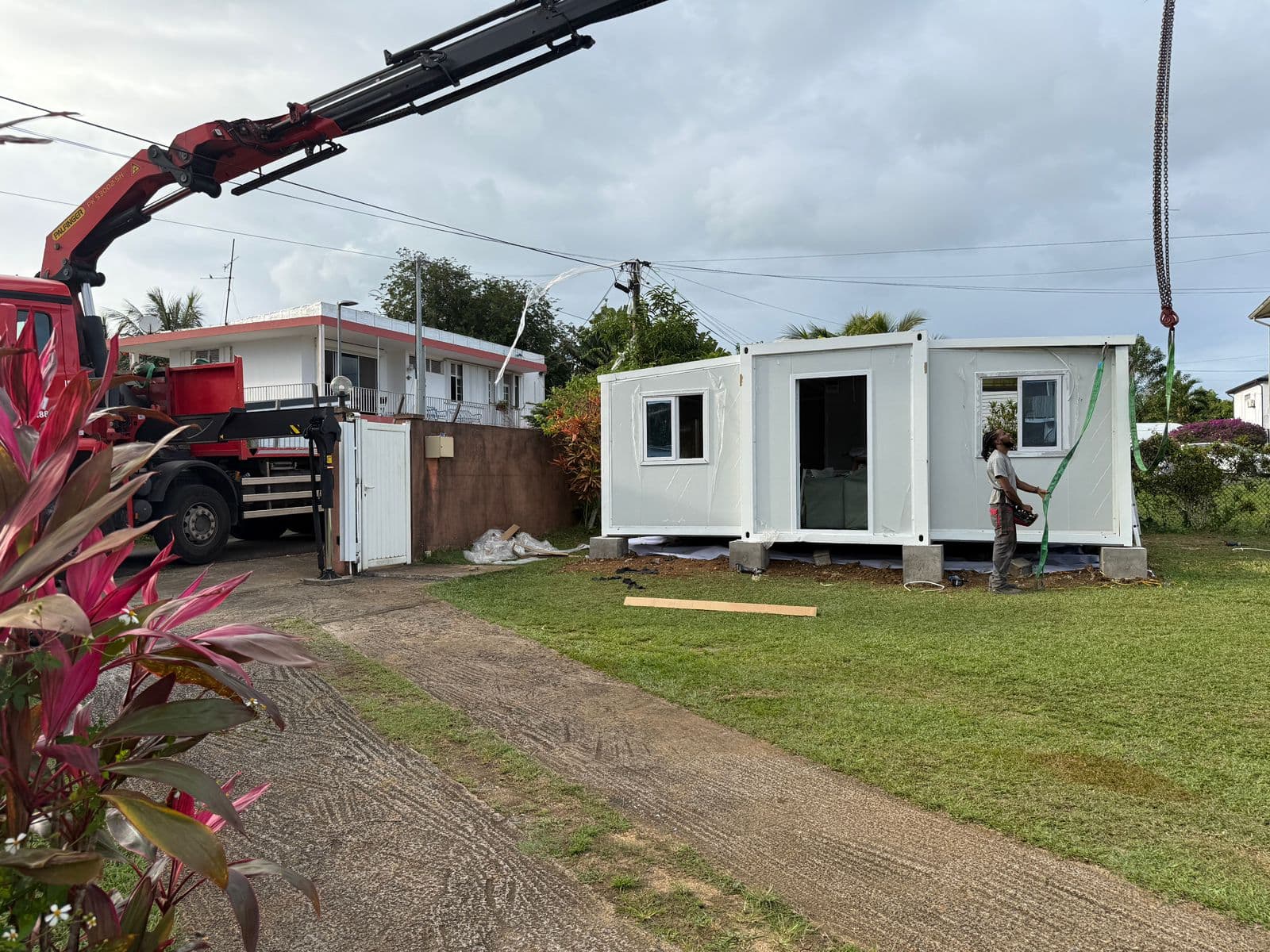 White expandable home being set in place by a crane during delivery.