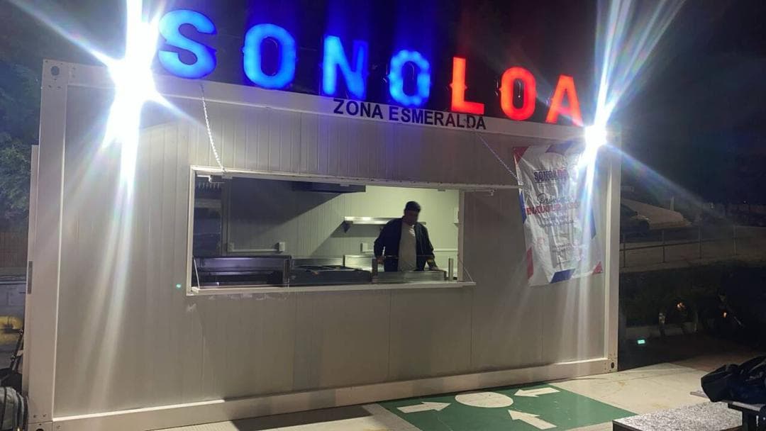 Deployed container food stand with custom illuminated signage at night.